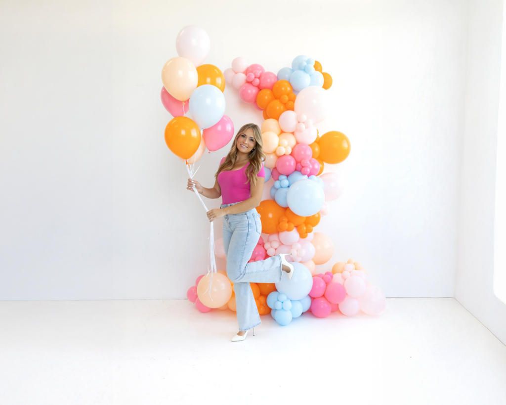 Maui’s Balloons owner beside a bright pink, orange and blue balloon arch during her brand shoot