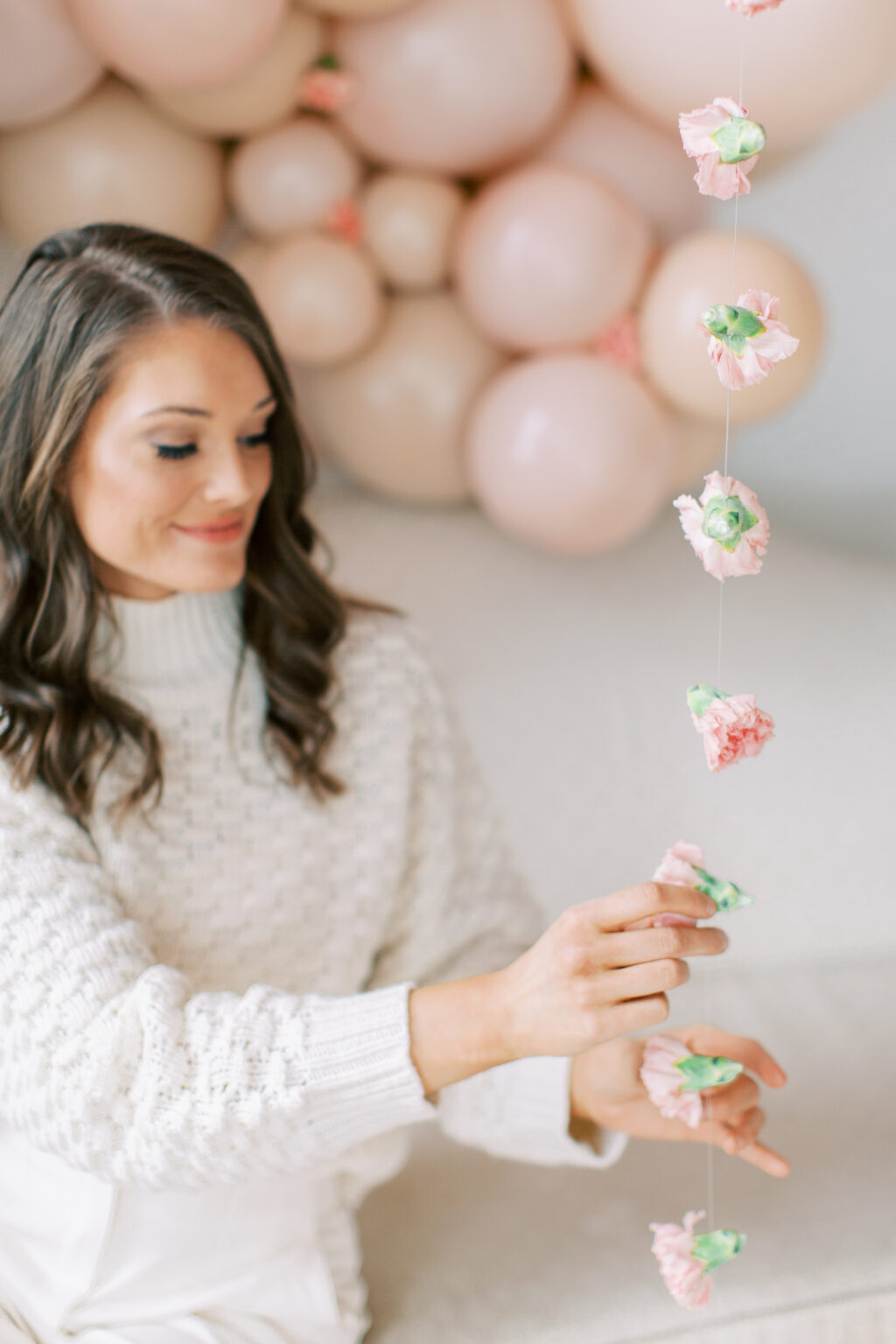 The Posh Balloon owner adding floral details to a blush balloon garland