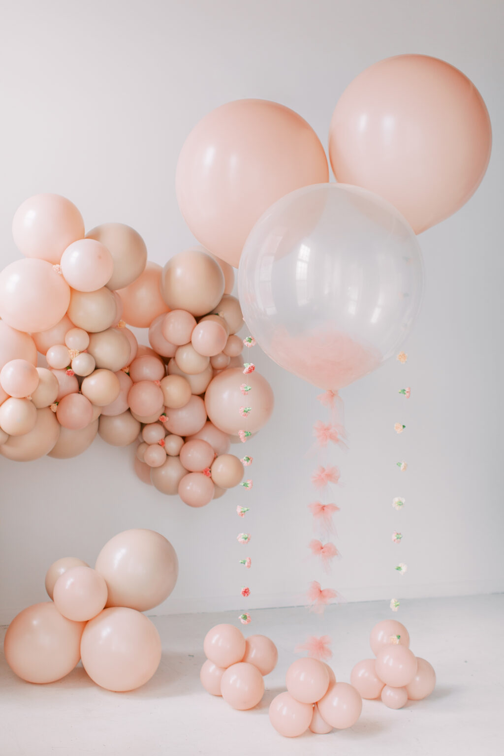 Blush balloon arrangement with a clear balloon and tassel tail by The Posh Balloon