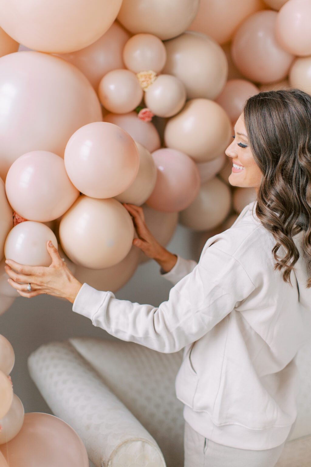 The Posh Balloon owner placing balloons into a blush organic garland