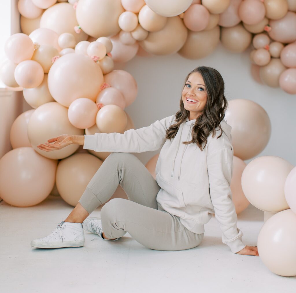 The Posh Balloon owner sitting in front of an oversized blush balloon installation