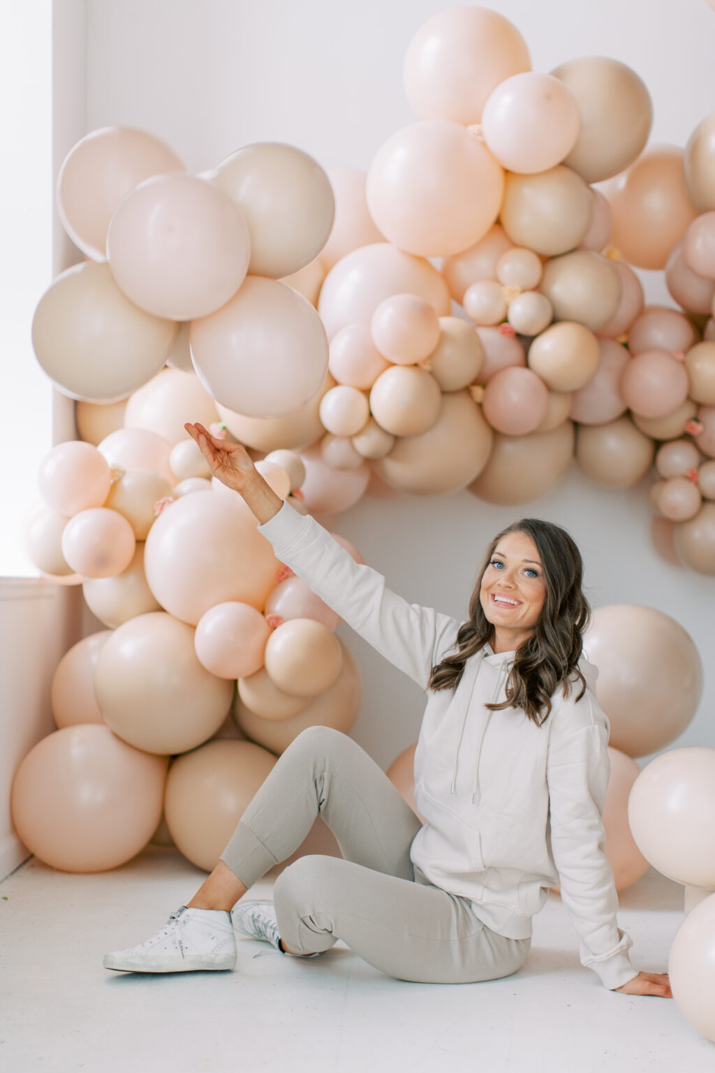 The Posh Balloon owner reaching up into a blush balloon installation