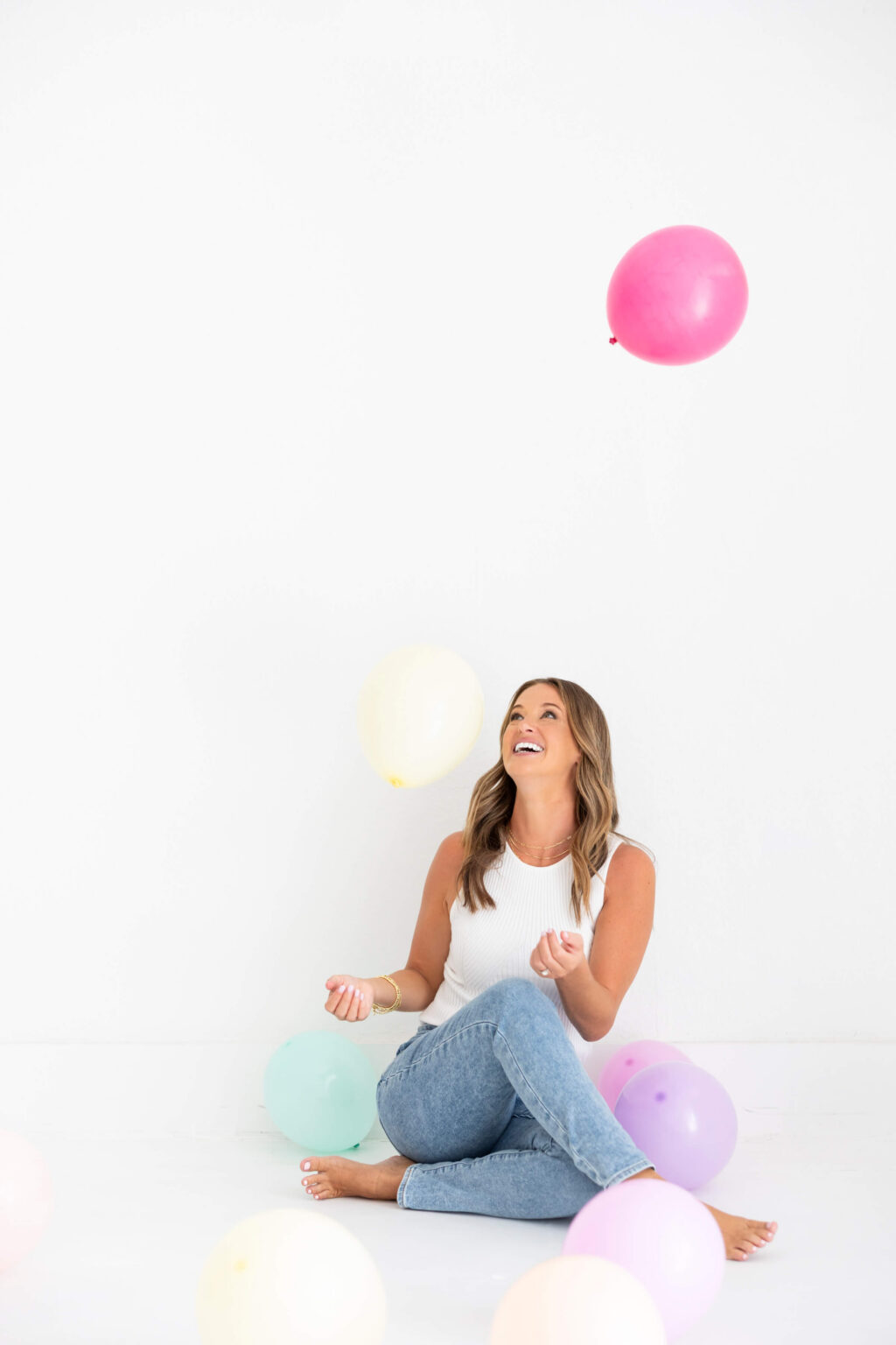 Kathryn of Daydream Sites sitting on the floor with pastel balloons during her brand photoshoot