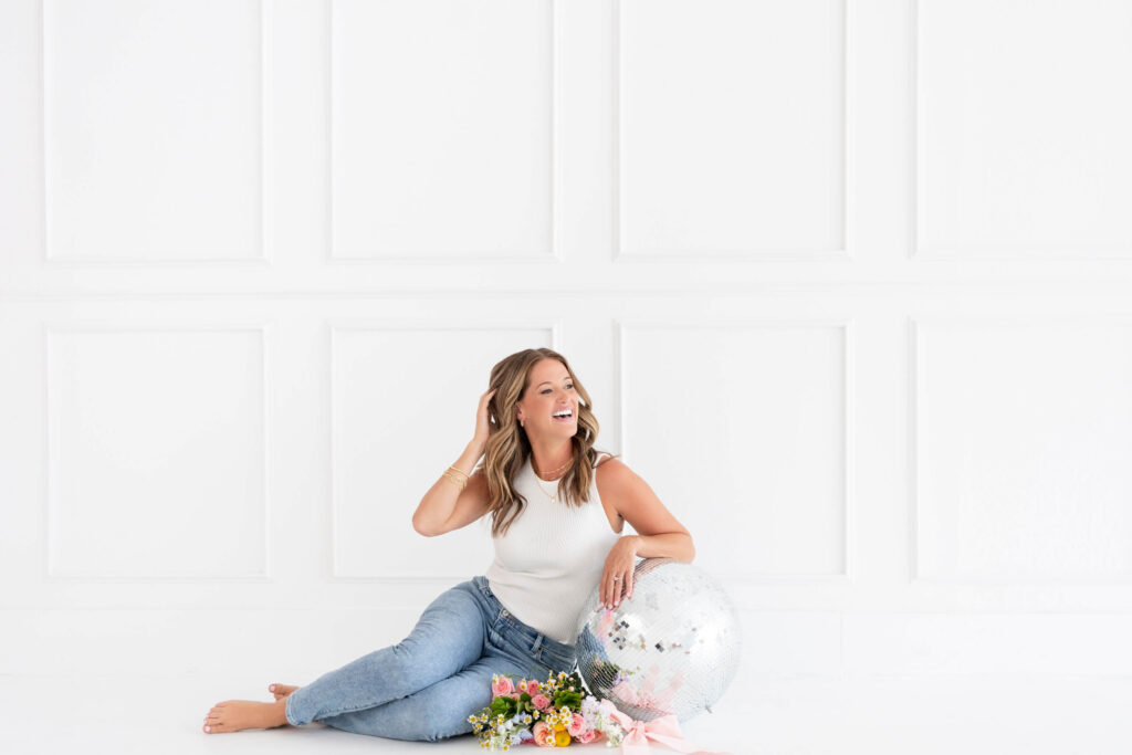 Kathryn of Daydream Sites sitting on the floor in a white top with a disco ball during her brand shoot
