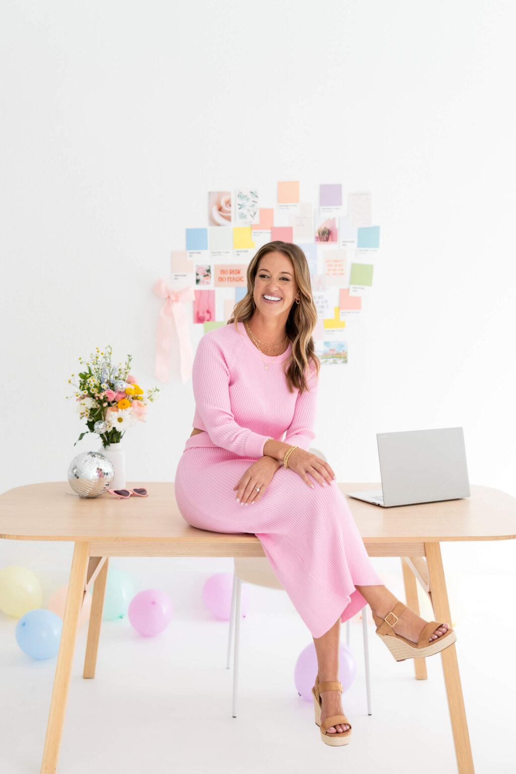Kathryn of Daydream Sites working at a desk in front of a colourful mood board